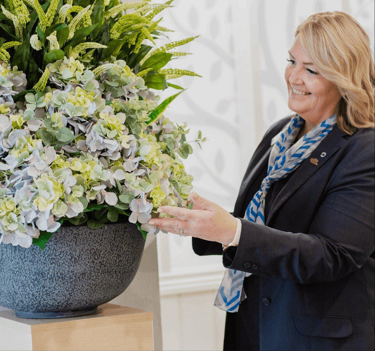 An image of a female funeral director looking at and prepping flowers