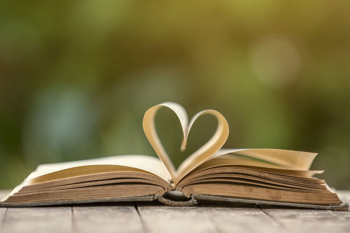 An image of an open book which has the middle pages arranged in a shape of a heart