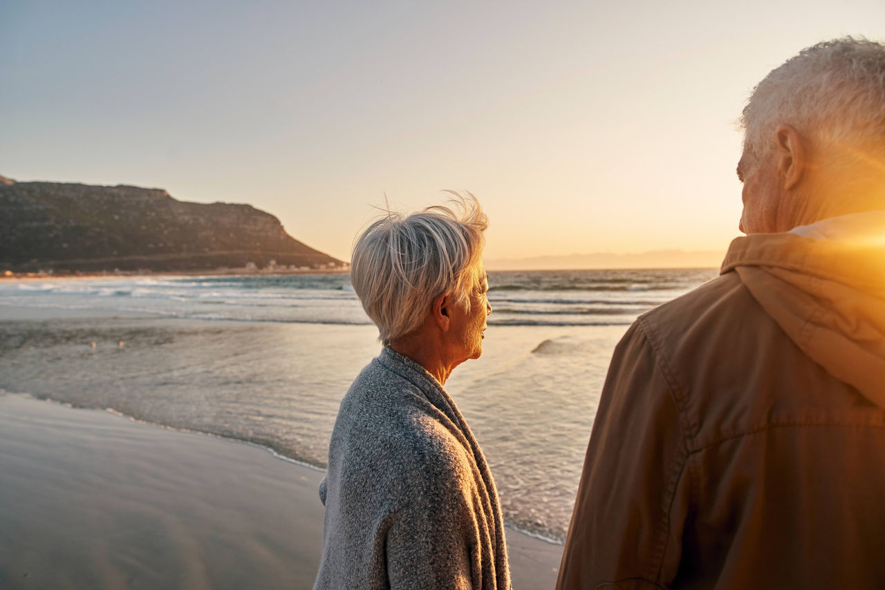 A man and a woman looking off into the sunset at the beach